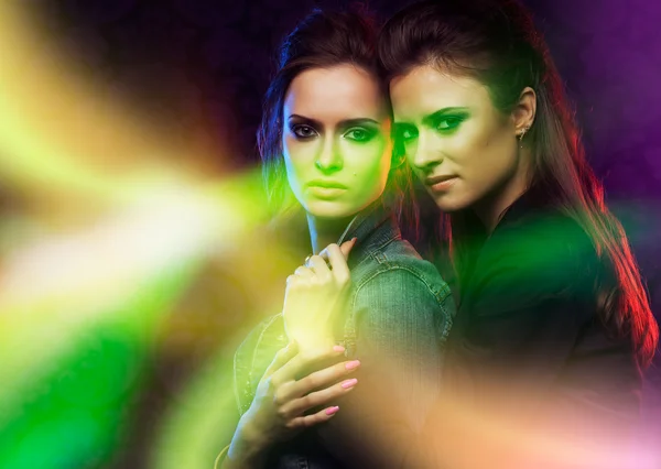 Kvinnliga tvillingar i färgat ljus ränder. — Stockfoto