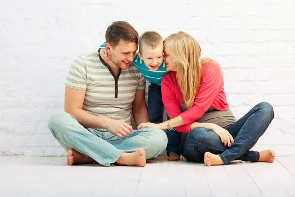 三个坐在墙边的地板上和笑幸福的家庭 爸爸和小男孩 母亲是怀孕 — 图库照片