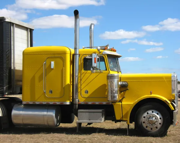 Gele vrachtwagen tegen blauwe hemel — Stockfoto