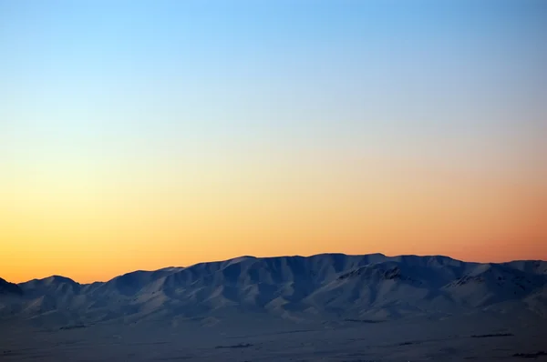 Ηλιοβασίλεμα πάνω από τα χιονισμένα βουνά — Φωτογραφία Αρχείου