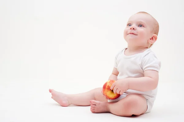 Baby with apple sitting on the floor — Stock Photo, Image