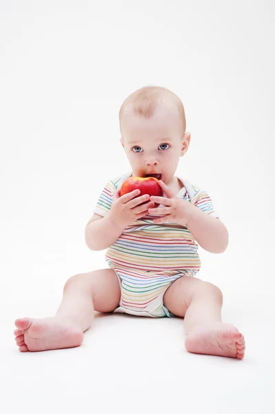 Мальчик сидит на полу и ест яблоко — стоковое фото