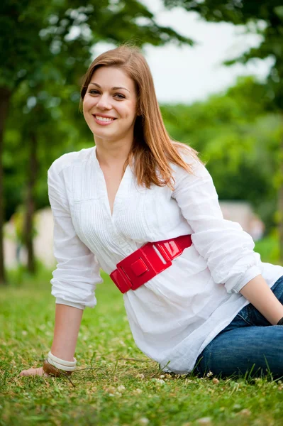 Beautiful young woman sitting at the grass — Stock Photo, Image