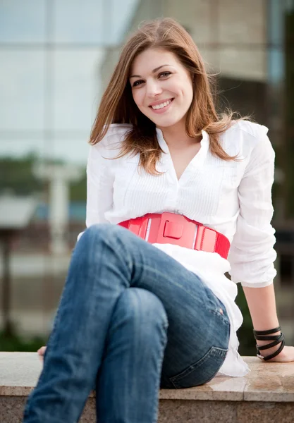 Молода усміхнена жінка сидить — стокове фото