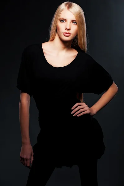 Junge Blondine posiert vor dunklem Hintergrund — Stockfoto
