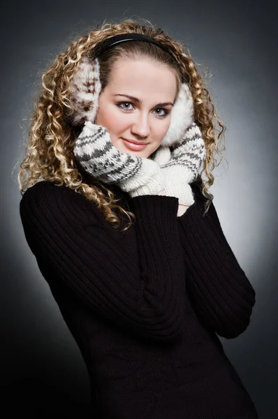 Curly young woman in furs earphone and mitten — Stock Photo, Image