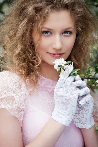 Schöne junge Frau in weißen Handschuhen mit Blumen — Stockfoto