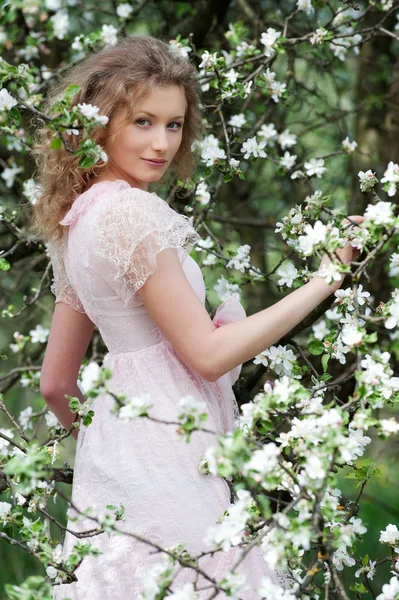 Model in pink dress posing in white flowers — Stock Photo, Image