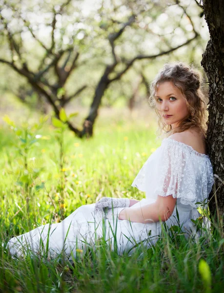 Женщина в белом платье сидит на траве — стоковое фото