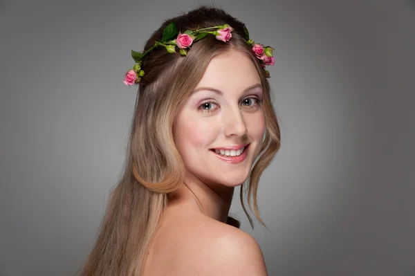 Jovem graciosa com rosas na cabeça — Fotografia de Stock