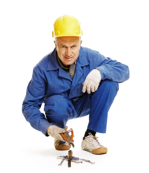 Workman duduk di lantai dan memegang penjepit — Stok Foto