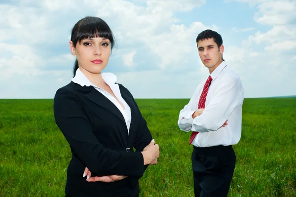 Empresários sérios em pé no prado verde — Fotografia de Stock
