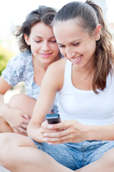 Дві молоді жінки дивляться на мобільний телефон — стокове фото
