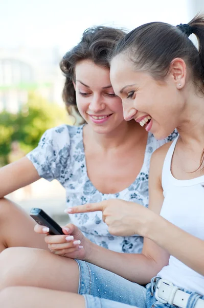 Женщины смеются и смотрят на мобильный телефон — стоковое фото