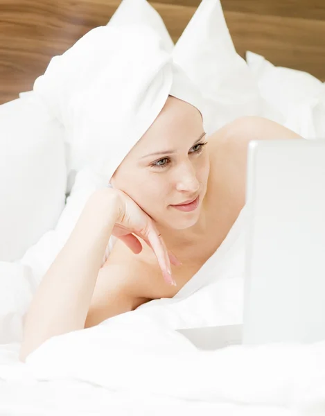 Beautiful woman lying in the bed with laptop — Stock Photo, Image