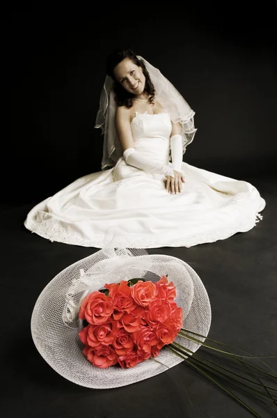 Bruid zittend op de vloer met bos van rozen aan de voorkant — Stockfoto