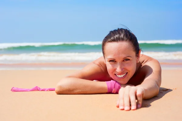 Fröhliche Frau auf dem nassen Sand liegend — Stockfoto