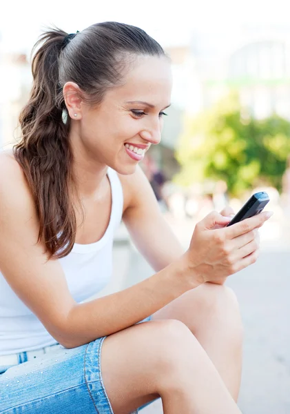 Šťastná mladá žena s mobilním telefonem — Stock fotografie