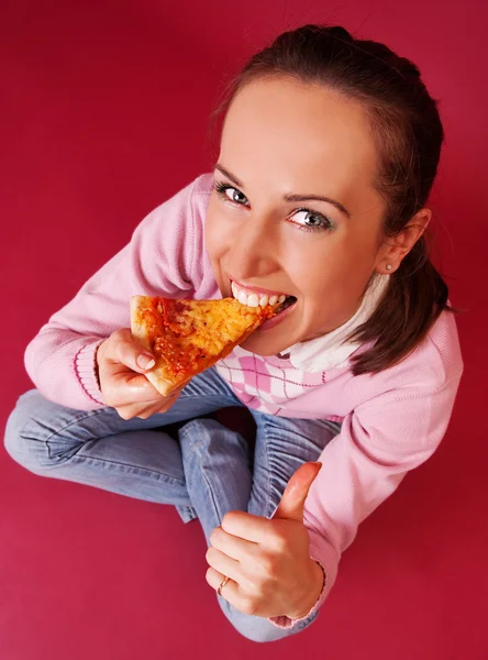 Красива жінка їсть піцу і показує великі пальці вгору — стокове фото