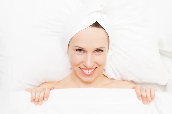 Mujer sonriente en toalla acostada en la cama —  Fotos de Stock
