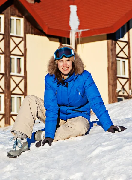 Kobieta siedzi na śniegu przed budynek hotelu — Zdjęcie stockowe