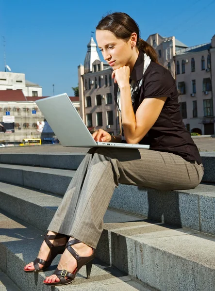 Woman sitting on the stairs with laptop — Stock Photo, Image
