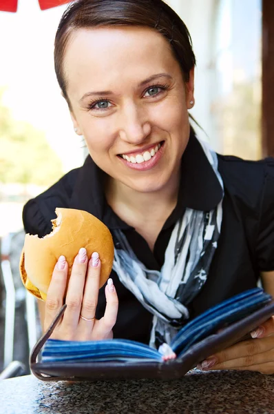 Kobieta z burger czytanie książki — Zdjęcie stockowe