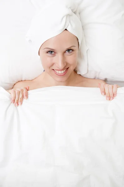 Ung kvinna med vackert leende liggande i sängen — Stockfoto