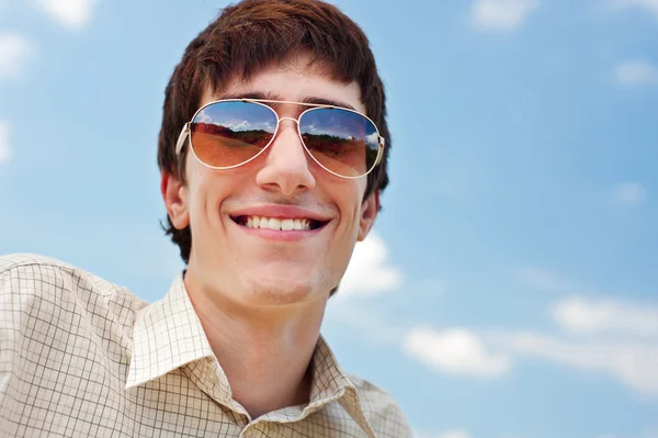Gelukkig man in zonnebril tegen blauwe hemel — Stockfoto