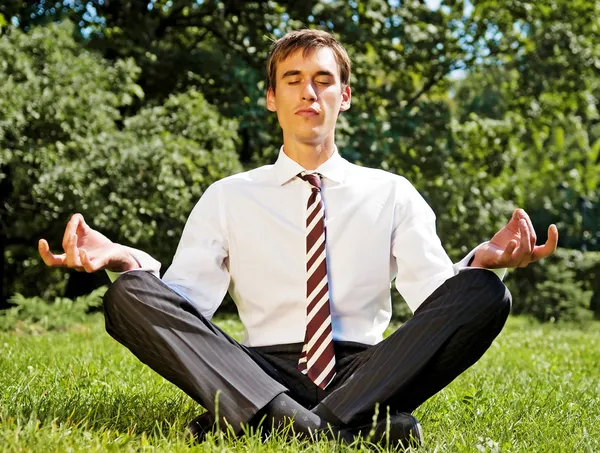 Businessman meditating on the grassland — Stock Photo, Image
