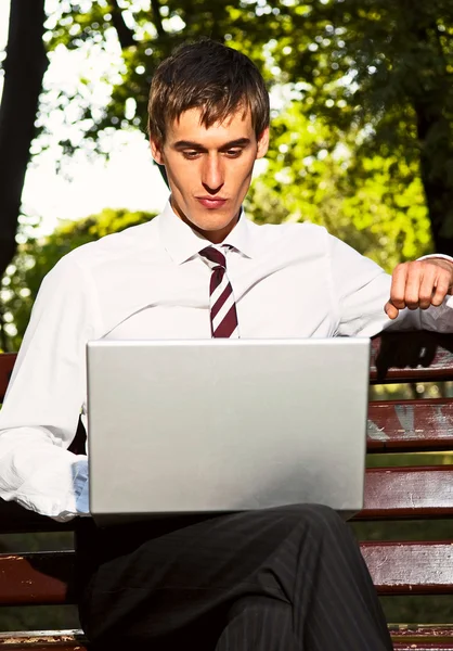 Zakenman zitten in het park met laptop — Stockfoto