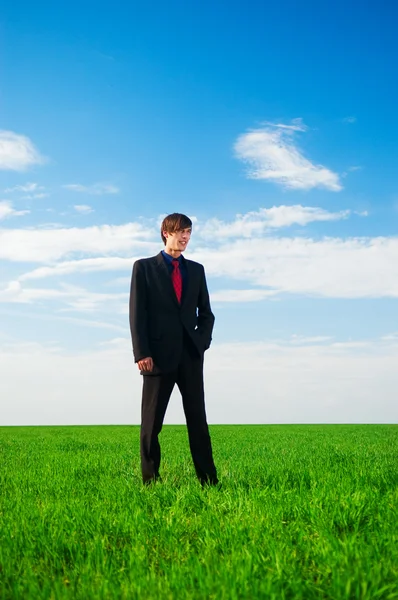 Serious businessman standing at the grass — Stock Photo, Image