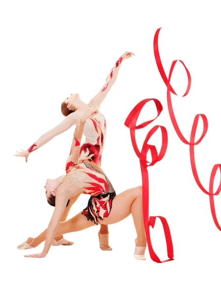 Two flexible gymnasts dancing with red ribbons — Stock Photo, Image