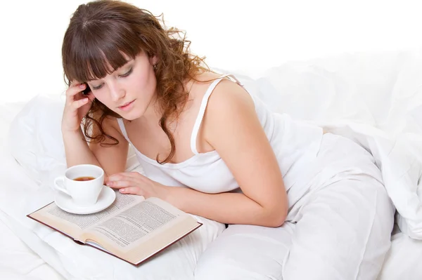 Kobieta w łóżku z książką i filiżanką kawy — Zdjęcie stockowe