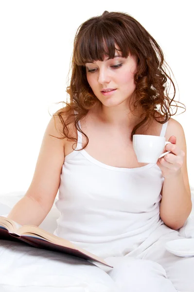 Молода жінка сидить у ліжку з книгою — стокове фото