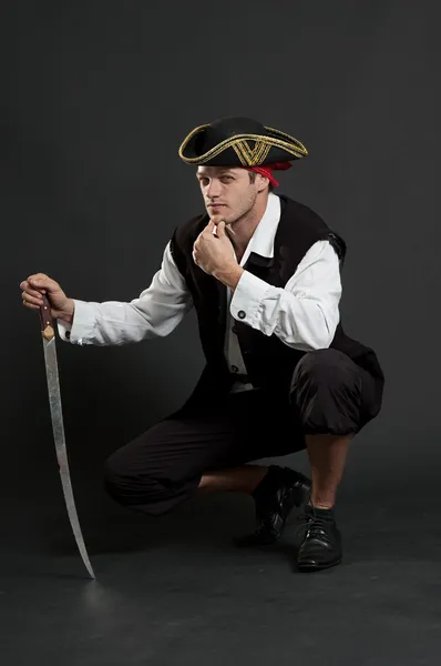 Serious pirate with sabre sitting — Stock Photo, Image