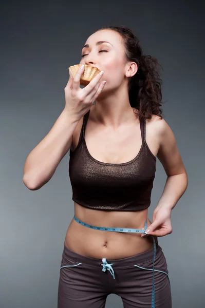 Mulher desportiva comer bolo com prazer — Fotografia de Stock