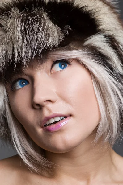 Attractive woman in fur hat looking up with interest — Stock Photo, Image