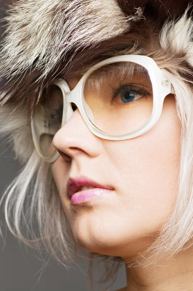 Junge schöne Blondine mit Pelzmütze und Sonnenbrille — Stockfoto