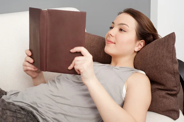 Mädchen liegt auf Sofa und liest Buch — Stockfoto