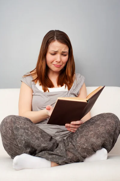 Грустная молодая женщина читает книгу — стоковое фото