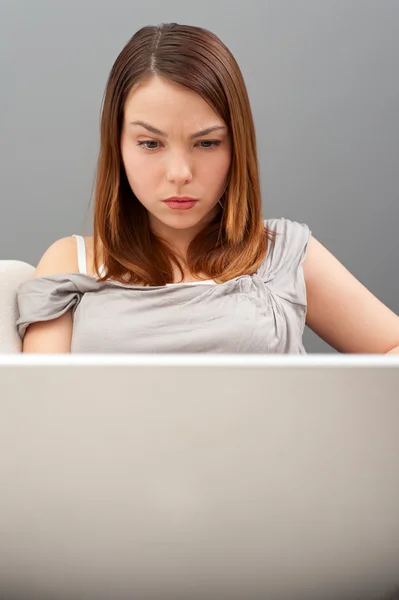 Серйозна молода жінка дивиться на ноутбук — стокове фото