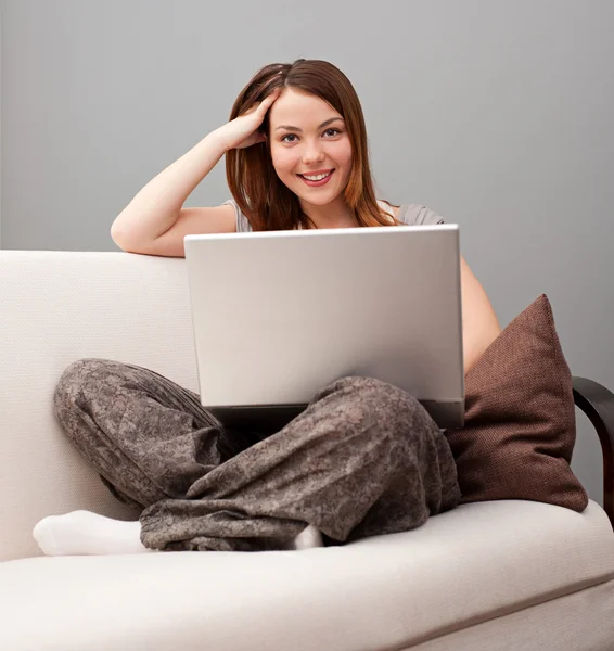 Smiley nő ül a kanapén, laptop — Stock Fotó