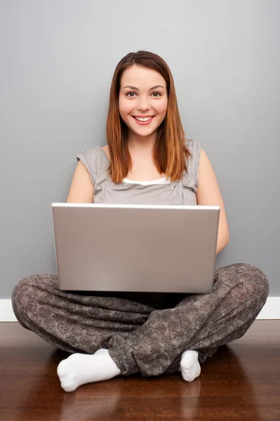 Smiley γυναίκα με φορητό υπολογιστή που κάθεται στο πάτωμα — Φωτογραφία Αρχείου