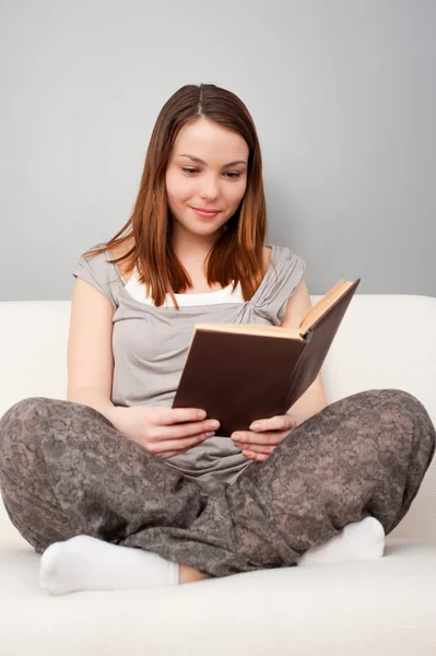 Mujer con libro sentado en el sofá —  Fotos de Stock