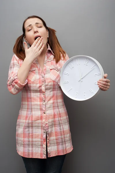 Mujer bostezando sosteniendo reloj — Foto de Stock