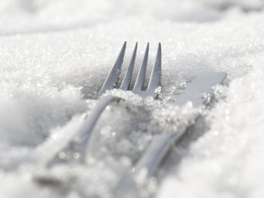 A fork and a knife lying in snow clipart