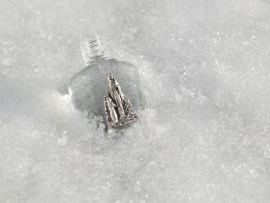 Holy water from Lourdes lying in snow and ice. clipart