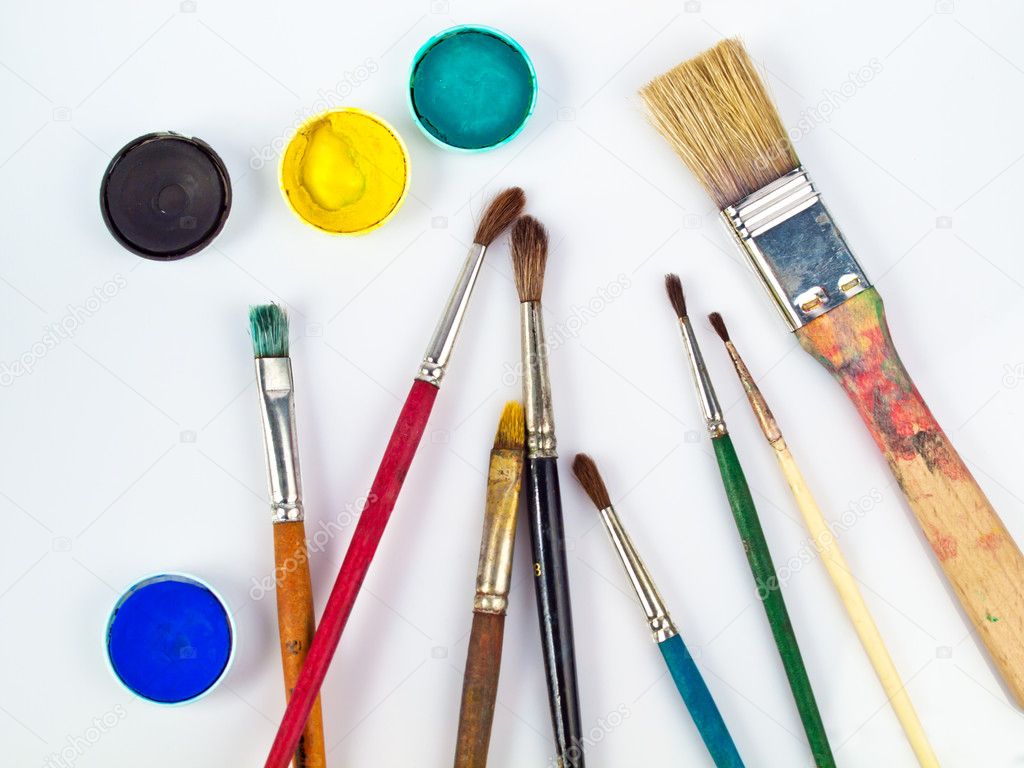 Paintbrushes and watercolors, art and craft equipment lying on a white table