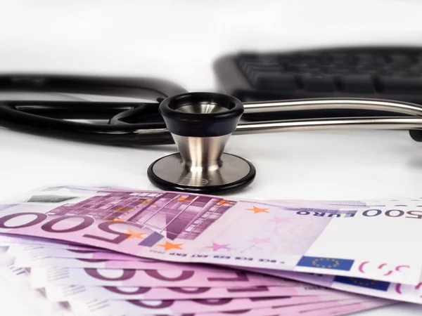 stock image Stack of 500 euro banknotes with a stethoscope and a keyboard in the background